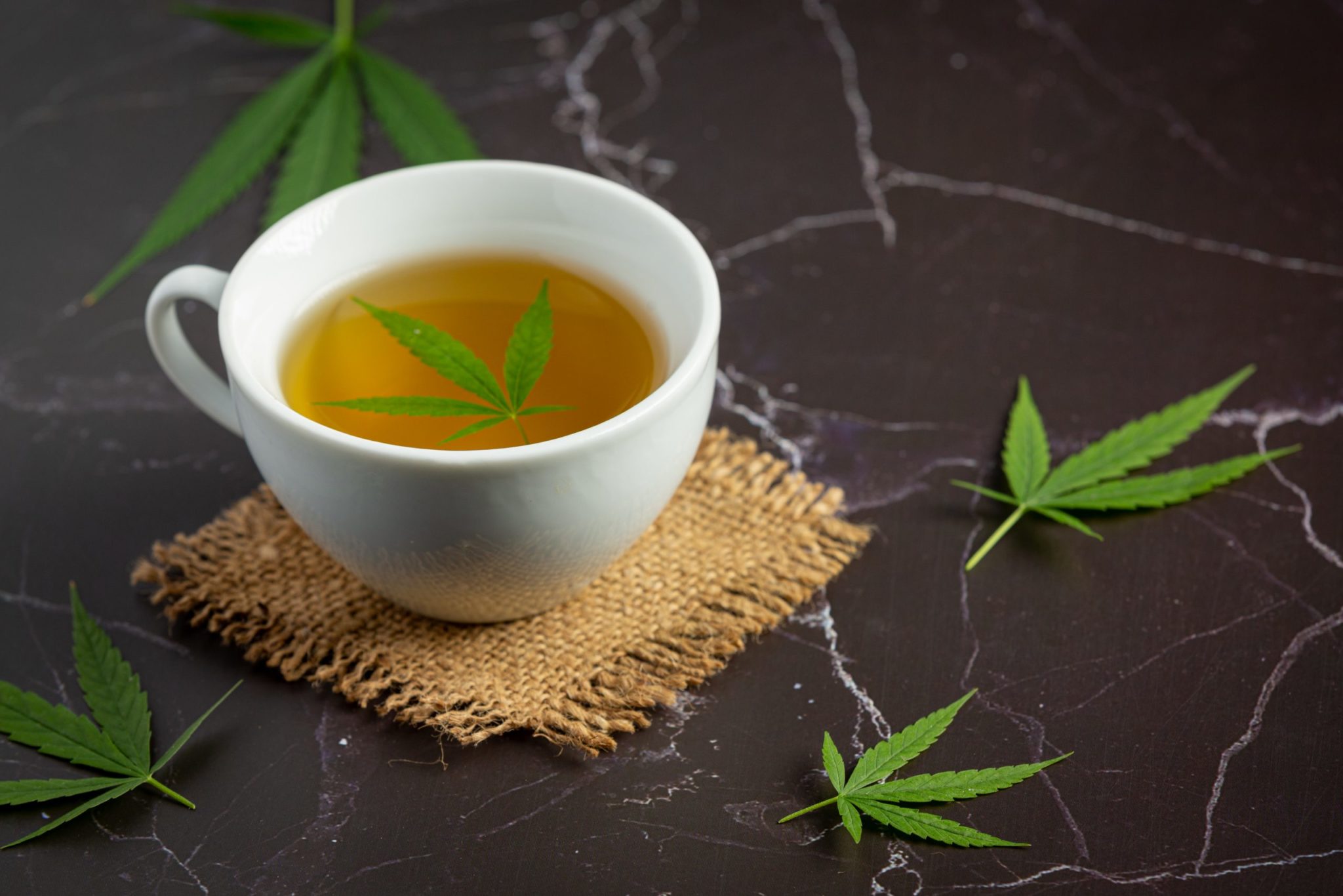 cup hemp tea with hemp leaves put black marble floor scaled